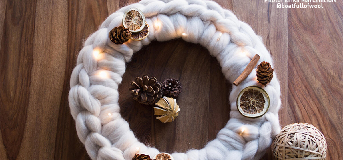 A circular wool wreath with pine cone and dried orange decoration