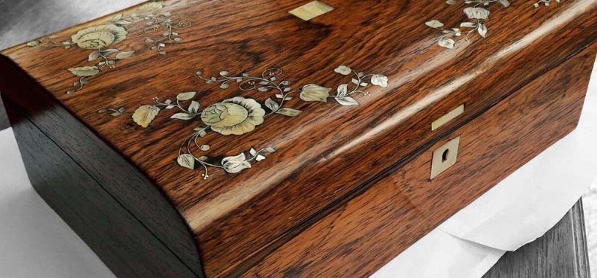 A polished wooden jewellery box with floral detail engraved on the lid.