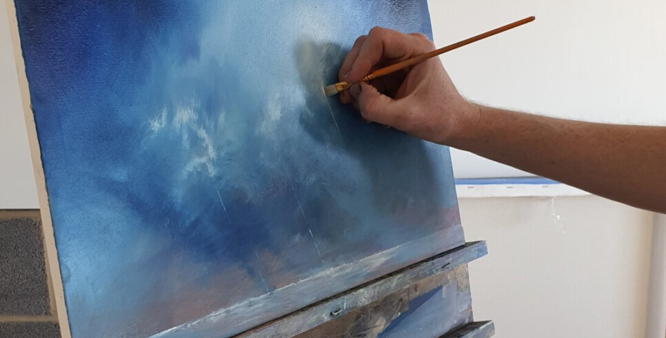 A blue oil painting on a canvas with someone hand painting with a paint brush