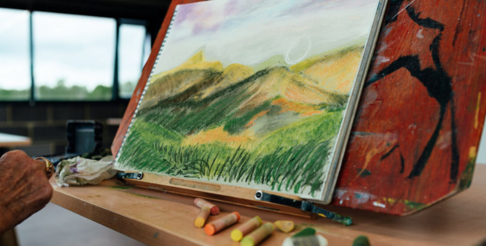 A person painting a beautiful green landscape with watercolours and pastels