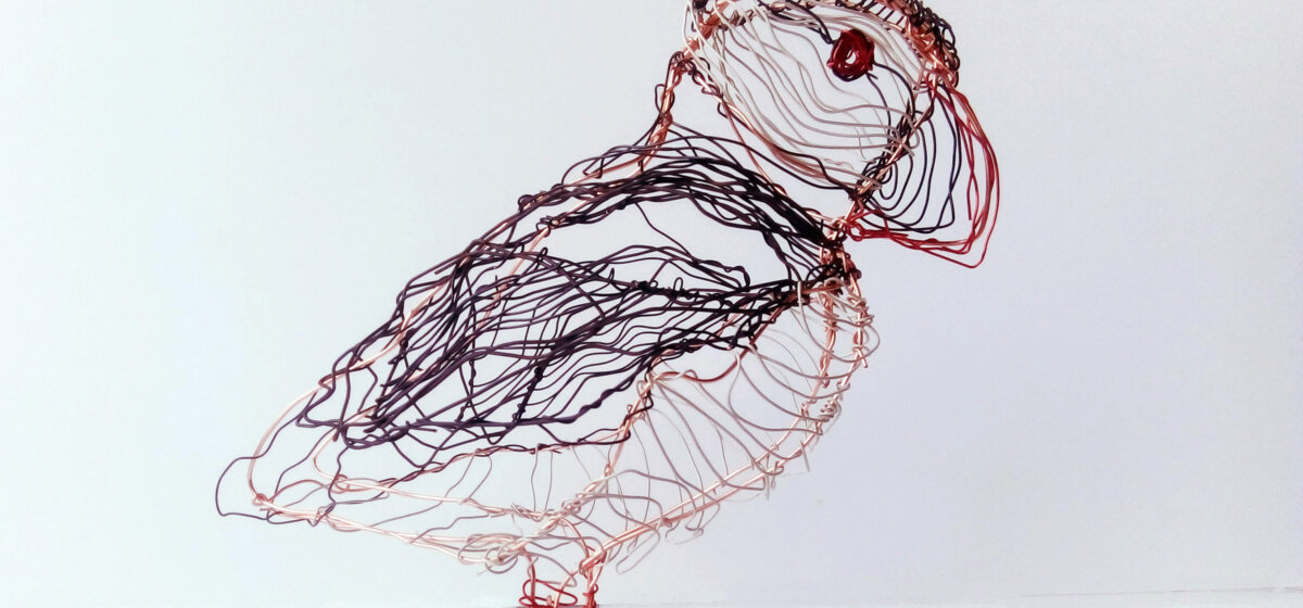Puffin made out of wire on a white background.