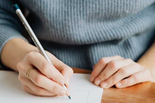 A person is drawing on a piece of white paper with a pencil.