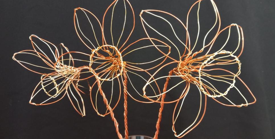 Three golden wire daffodils are photographed against a black background