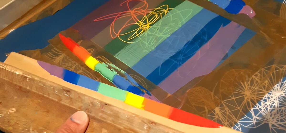 A screenprinting frame with a rainbow of paint