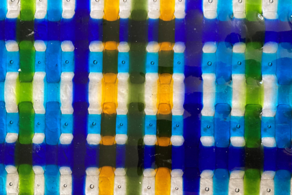 An image of latticed glass weaving into itself in colours yellow, light blue, green and royal blue.