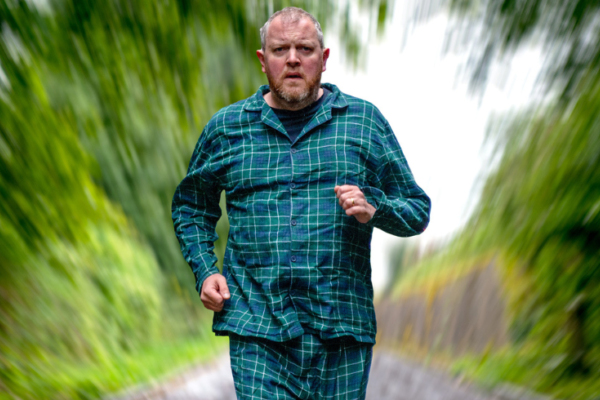 Miles Jupp running down a country lane in pajamas