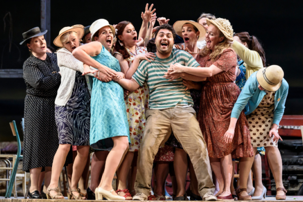 An image of the cast on stage in a group embrace facing the audience. They all have happy expressions.