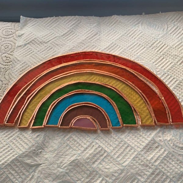 Kitchen roll with the arc shape pieces of different colour glass with a copper outline laid out like a rainbow