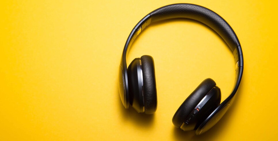 Some black over-ear headphones on a yellow background.