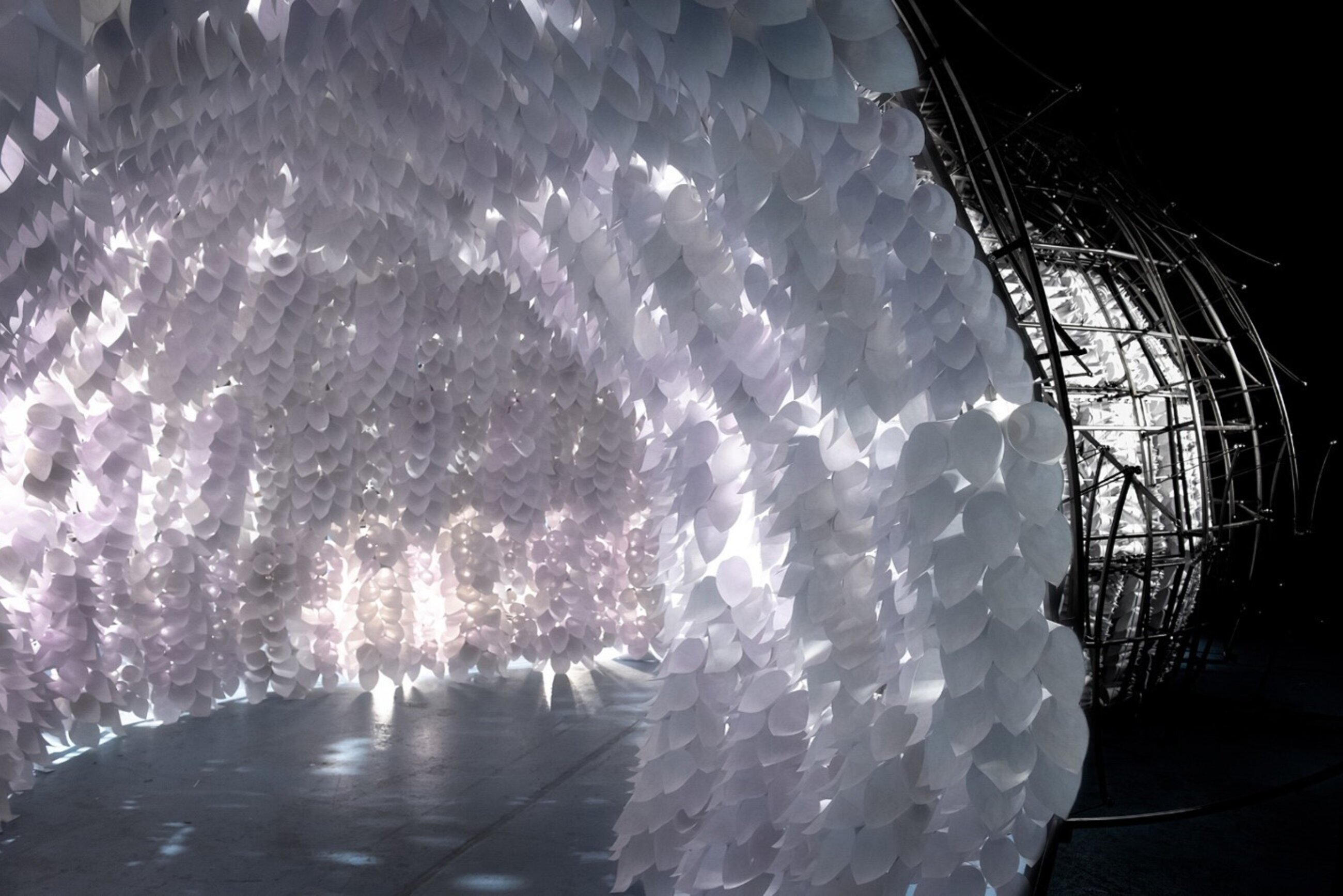 Breathing room Installation. In the image is a large tunnel of soft white decorations which blanket the inner tube walls of the tunnel and have light peeking through.