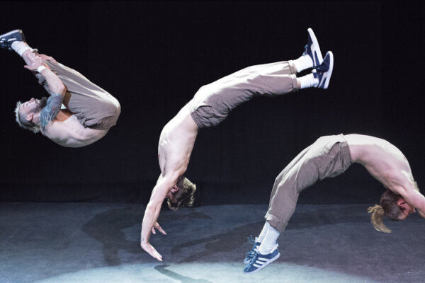 Three men flipping simultaneously across the stage