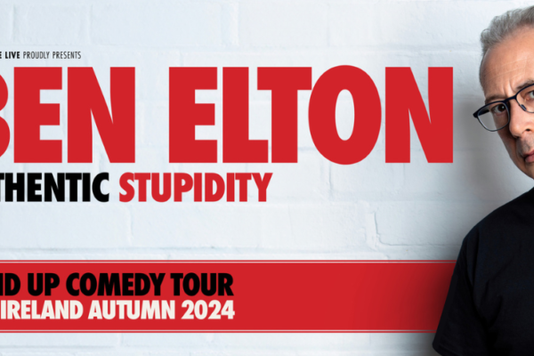A man against a white brick wall with red text behind him saying 'Ben Elton Authentic Stupidity'