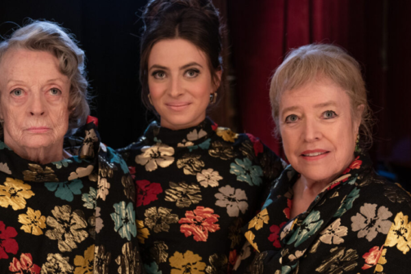 Three women (played by Laura Linney, Maggie Smith, Kathy Bates) stand wearing identical tops in a loud floral print.