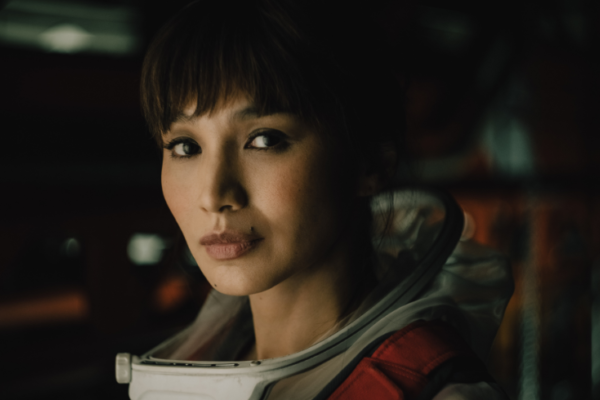 Actress Gemma Chan stands in a space suit smiling