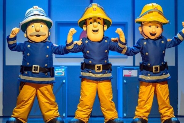three firemen stand with their arms up in their firemen costumes