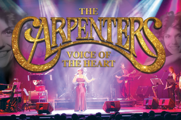 A woman on stage with a gold title of 'The Carpenters'