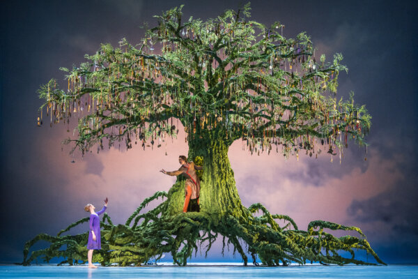 Two dancers dance on the roots of a large tree in the center of the stage in the live screening of The Winter's Tale at Corn Exchange Newbury