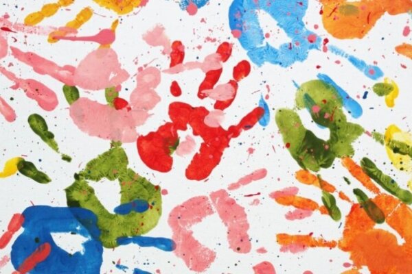 Layered colourful paint hand prints on white paper