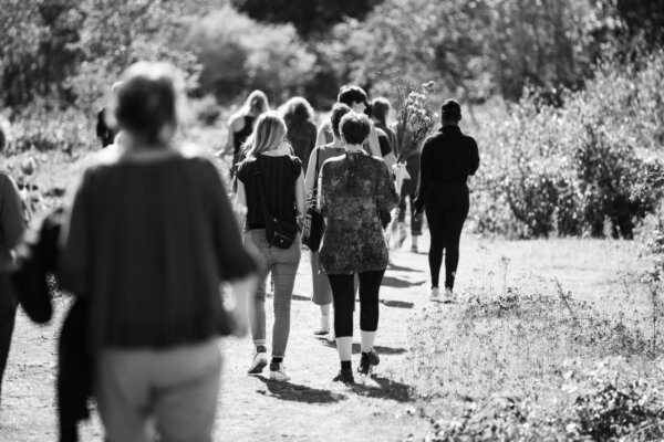 A group of people walk away from the camera along a path into the beautiful heathland landscape of Greenham Common.