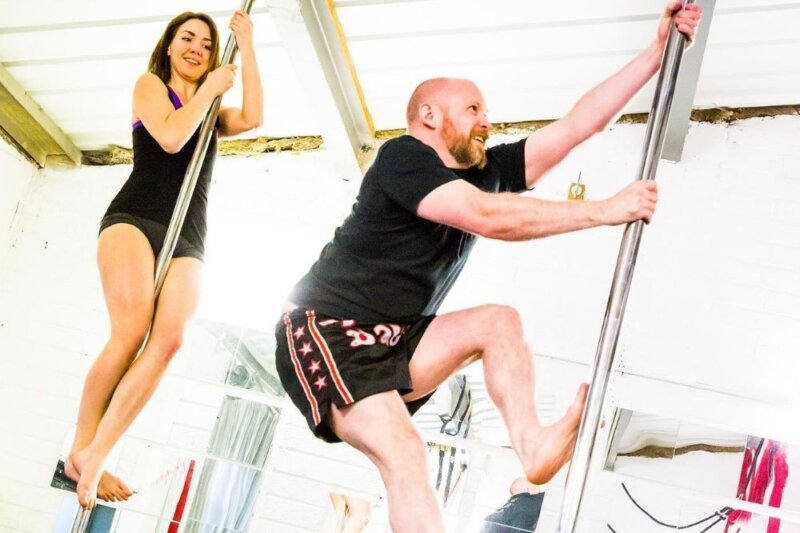 A man and a woman climbing poles as part of a pole fitness class at Spin City Newbury
