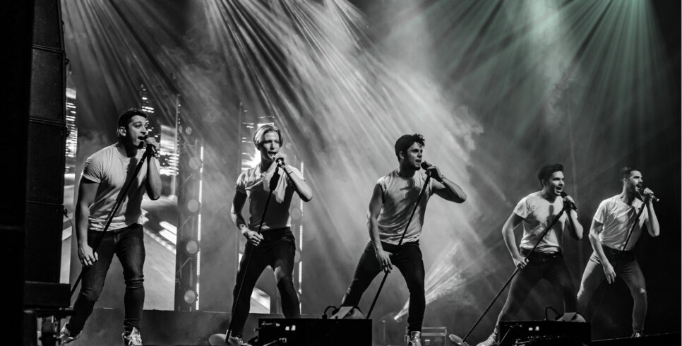 A boy band on stage in black and white, singing