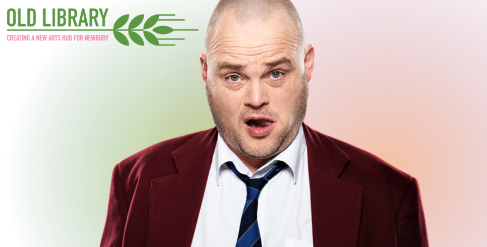 Al Murray in a burgundy suit jacket with a navy blue tie