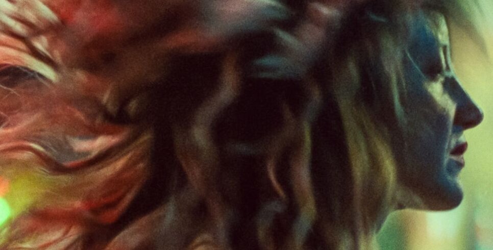An image of a woman's profile with long wavy hair blowing behind her