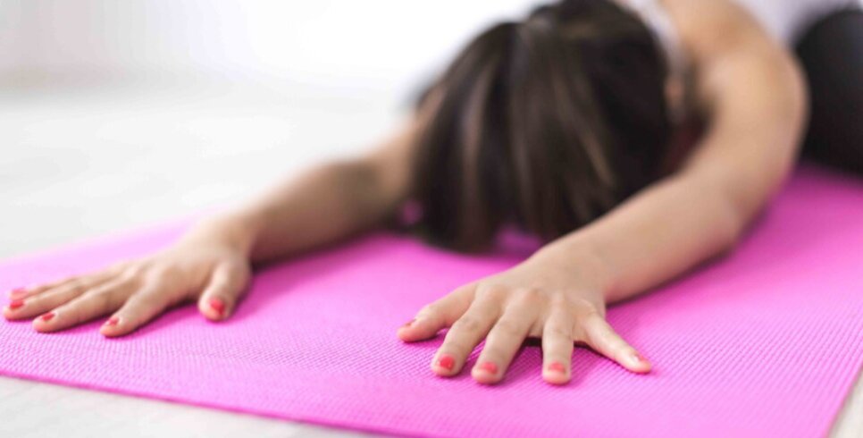 A photo of lady stretched out on a pink mat