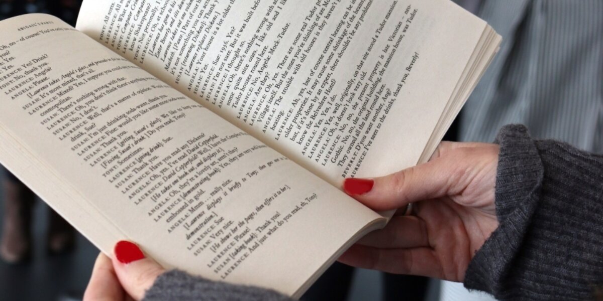 Angled close-up of a book that is held open with a pair of female hands.