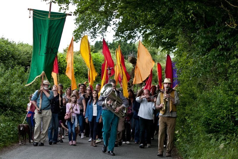 A band parades through the village of Aldworth followed by lots of red and yellow flags.