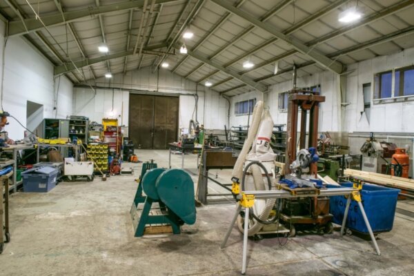An image of the metal workshop at 101 Outdoor Arts. Tools, work benches and toolboxes organised in large warehouse with pitched roof.