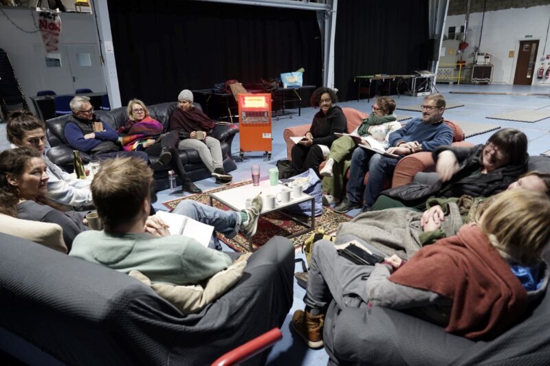 A group of people talking in a circle, seated on sofas.