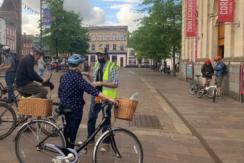 A volunteer steward guides cyclists who are gathering for Rider Spoke outside the Corn Exchange in Newbury.